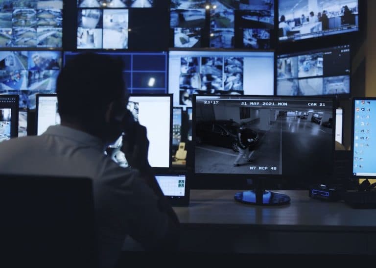 Security operator monitoring surveillance feeds in a command environment.